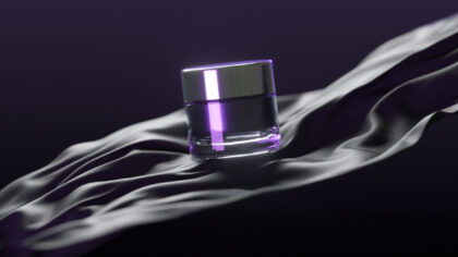 Elegant and modern perfume bottle with a purple shimmer is showcased on luxurious black silk, exuding sophistication and style